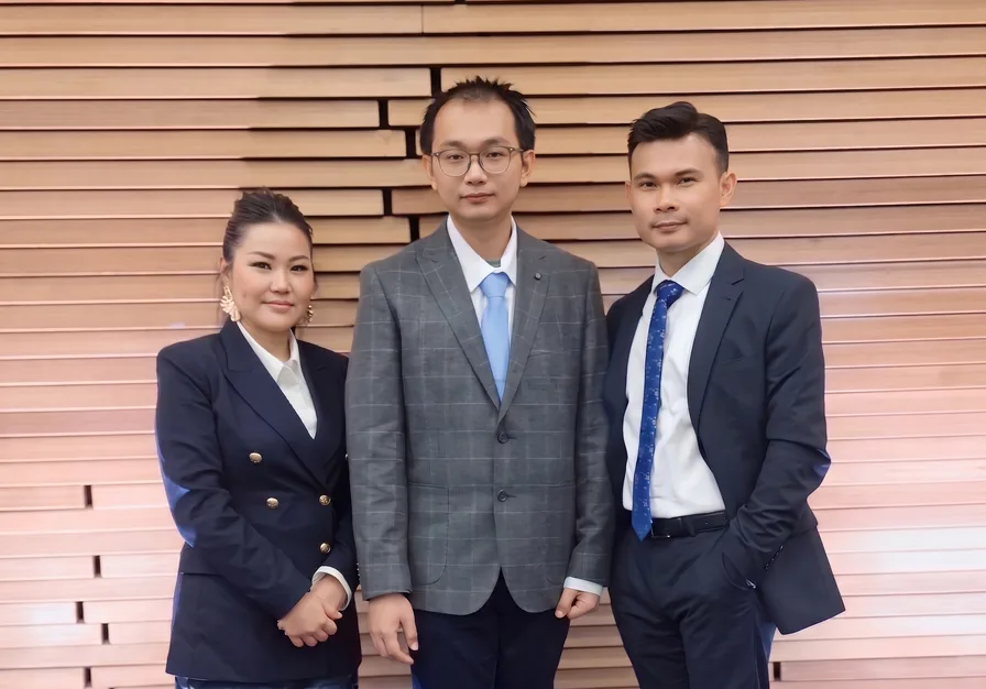 The Jellybytes team — three colleagues in business dress standing in front of a horizontal timber-slat wall